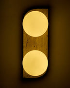 Travertine wall sconce illuminated with two warm white round glass globes mounted vertically on a wall.