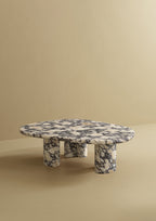 A low marble coffee table with an organic-shaped top and rounded legs.