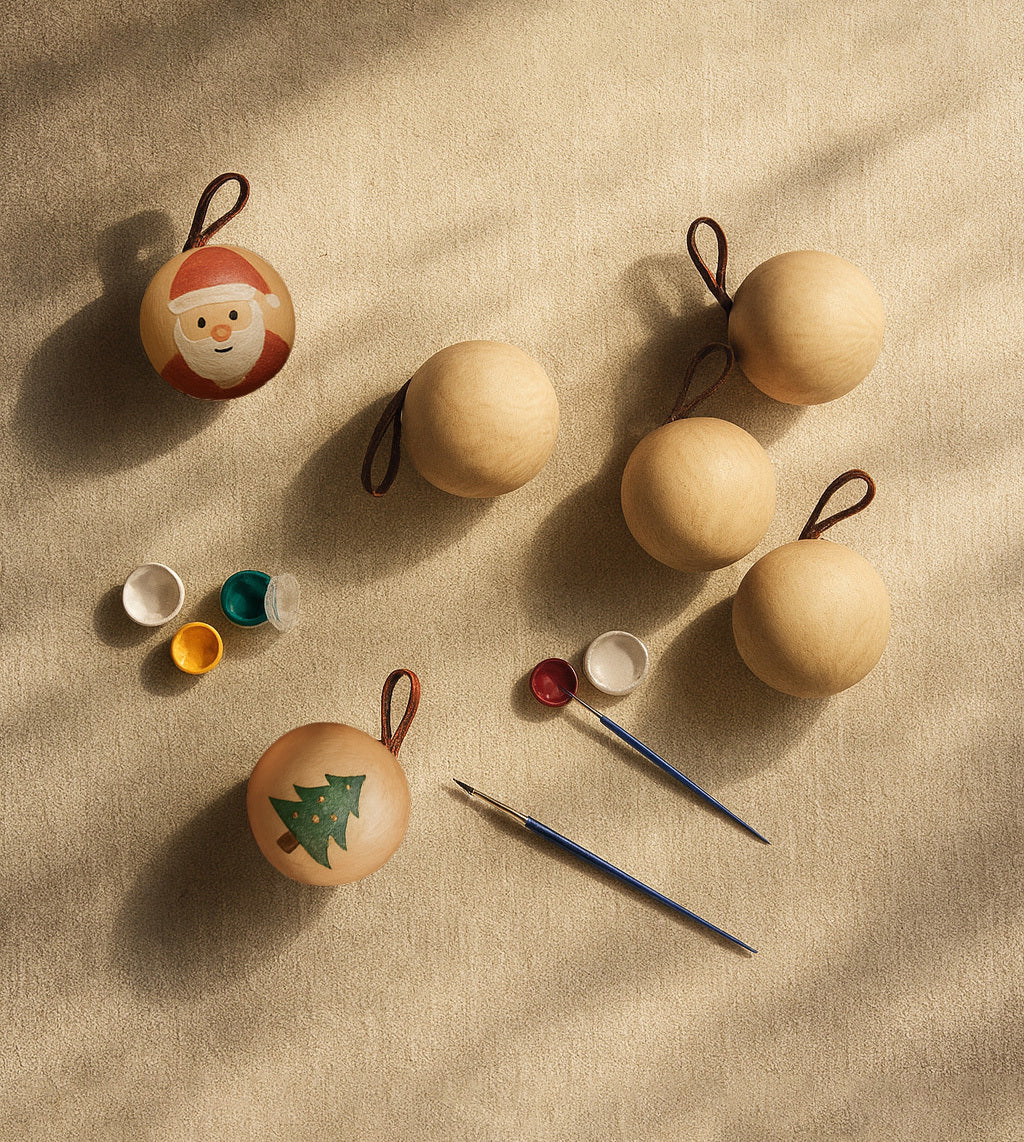 Bambino Wooden Ornaments with natural pine spheres, paint pots, and brushes, shown partially hand-painted for a holiday craft activity.