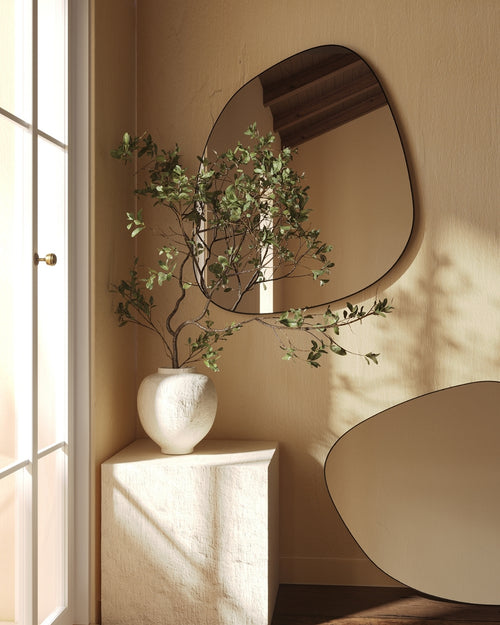 Organic blob-shaped frameless wall mirror with a soft asymmetrical silhouette, mounted on a neutral wall.