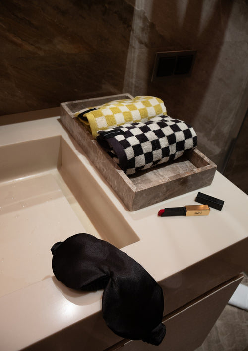 Folded checkered towels on a stone tray beside a bathroom sink.