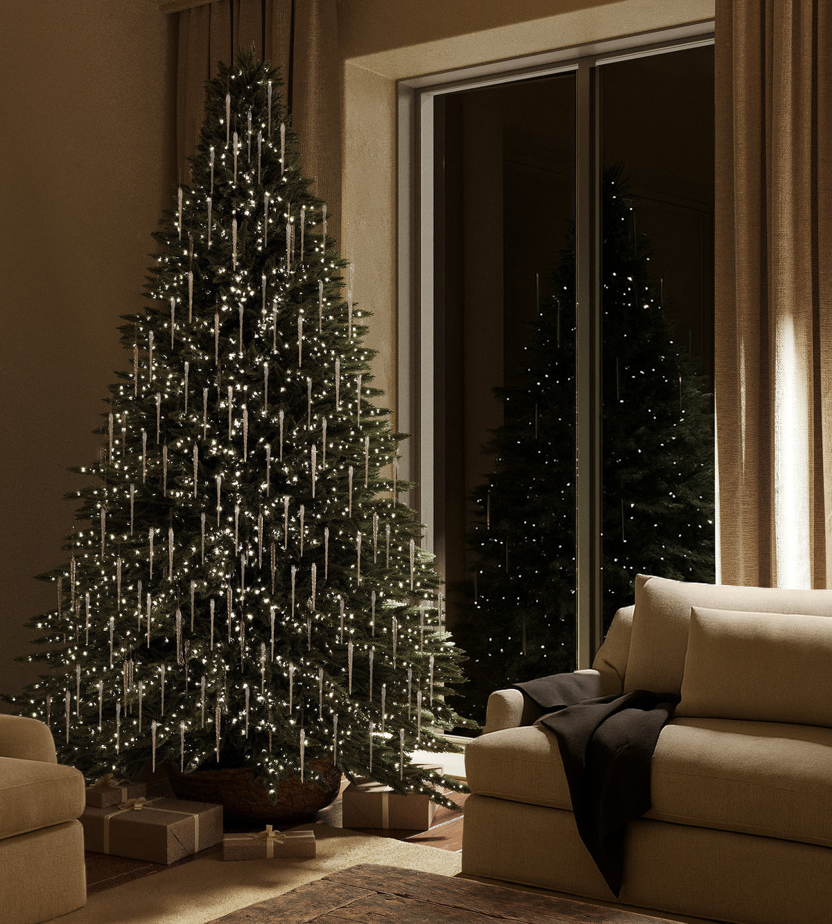 A Christmas tree decorated with clear glass icicle ornaments and warm white lights in a softly lit living room.