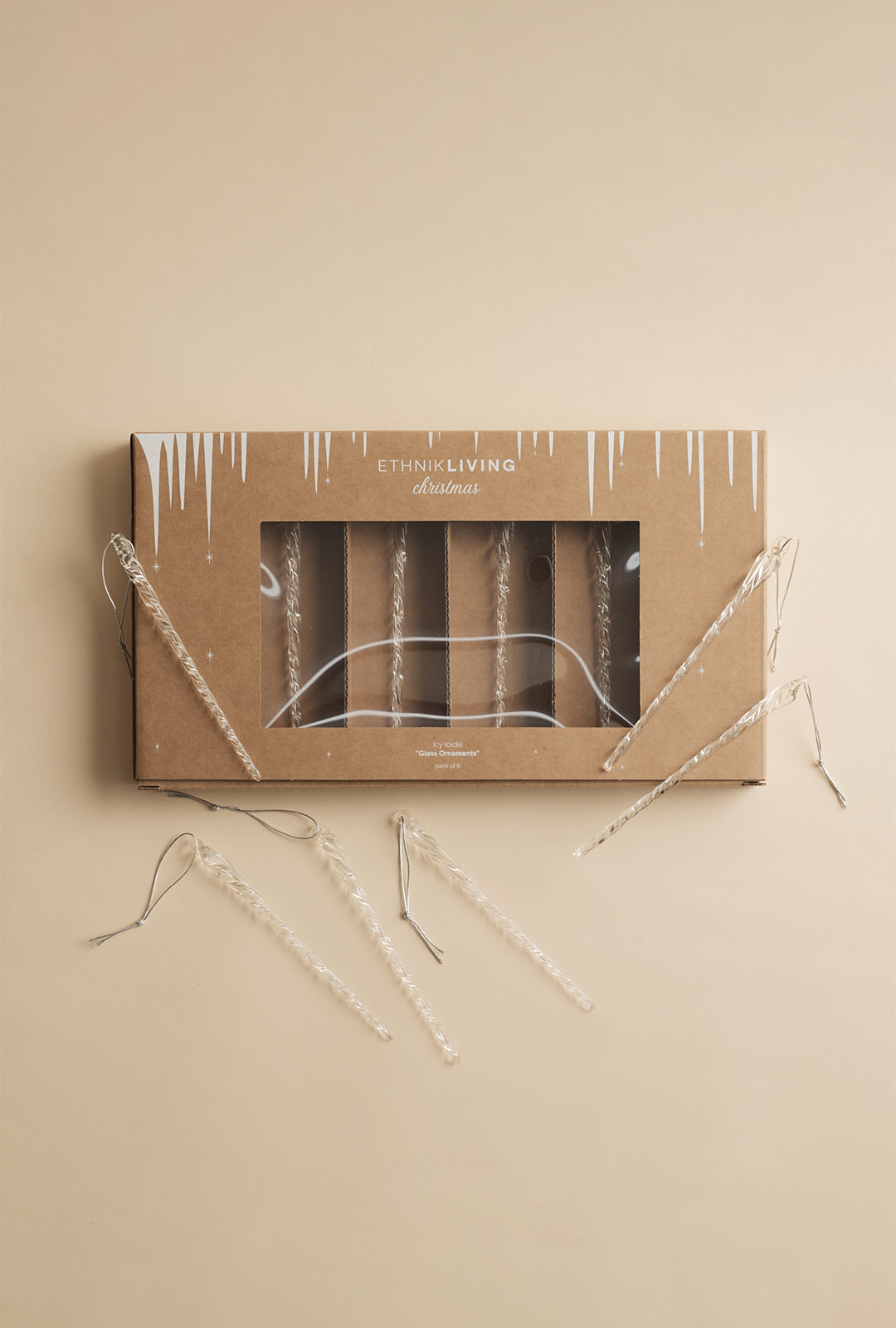 A set of six clear glass icicle ornaments displayed with their packaging on a neutral background.