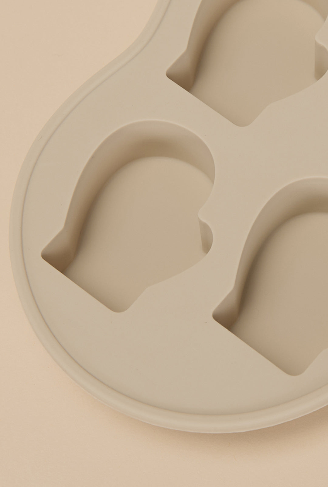 Detail view of a beige, mitten-shaped silicone mold with multiple recessed cavities.