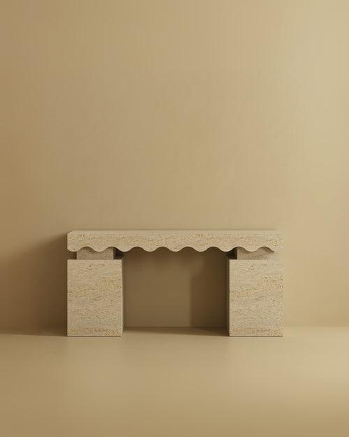 Travertine console table with a rectangular top featuring a scalloped carved edge and two solid block legs.