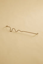 Wavy brass towel bar displayed on a neutral studio background.
