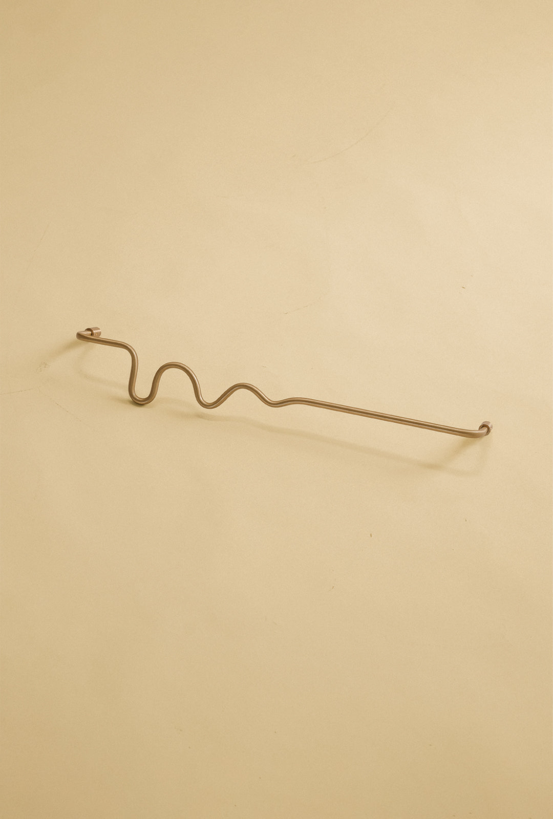 Wavy brass towel bar displayed on a neutral studio background.