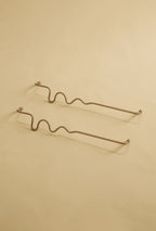 Two brass wavy towel bars displayed on a neutral studio background.