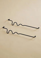 Two black wavy towel bars displayed on a neutral studio background.