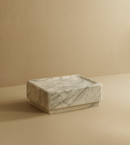 Square coffee table crafted from light marble with subtle gray veining, featuring a solid block form and a low-profile design.