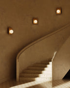 Clemence oak wood wall sconces with white glass globes installed along a curved staircase wall, emitting warm ambient light.