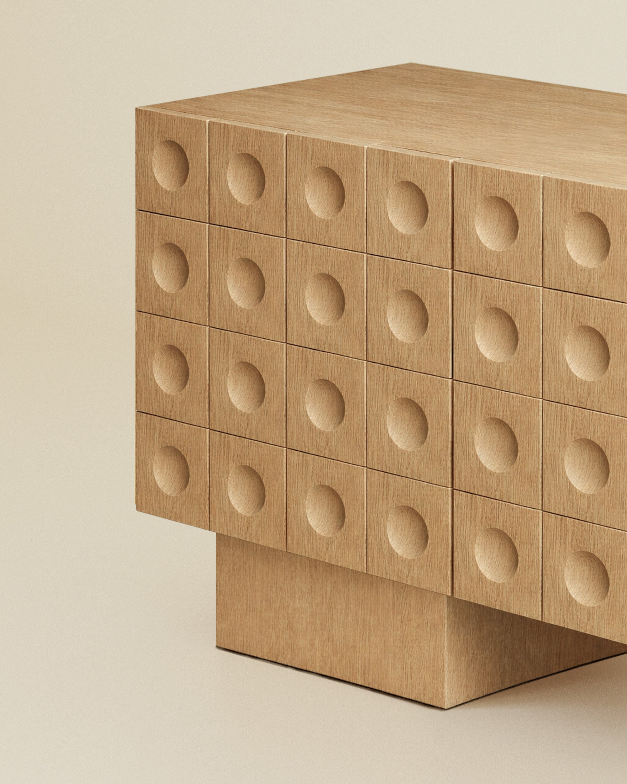 Angled close-up of a modern wood sideboard with circular indented drawer fronts and a solid block base.