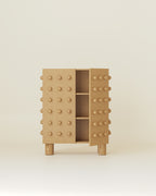 Wooden storage cabinet with a sculptural front of evenly spaced rounded wooden spheres, shown with one door open revealing interior shelving.