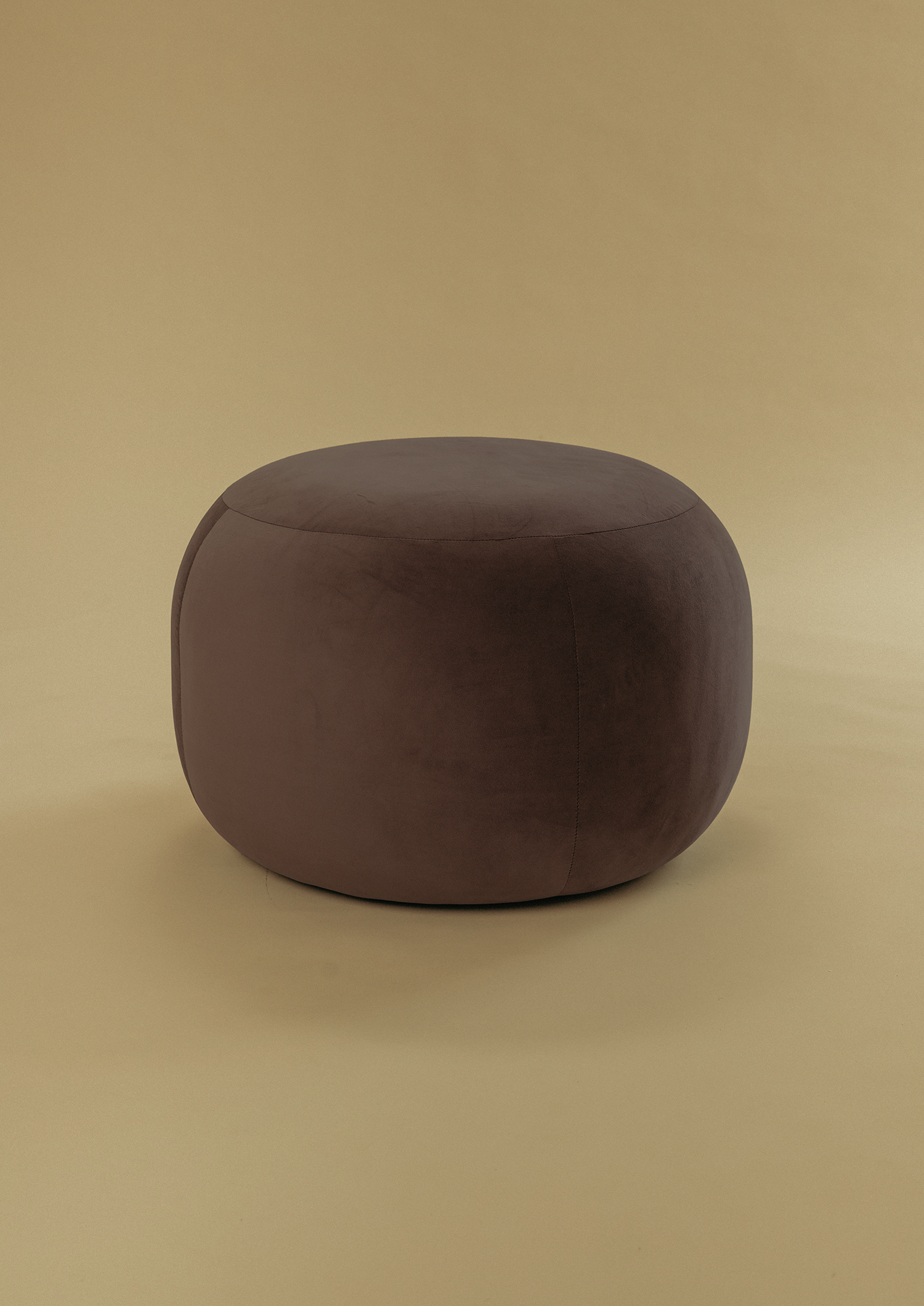 Small Pebble Ottoman in dark brown upholstery with a soft rounded form, photographed against a neutral backdrop.