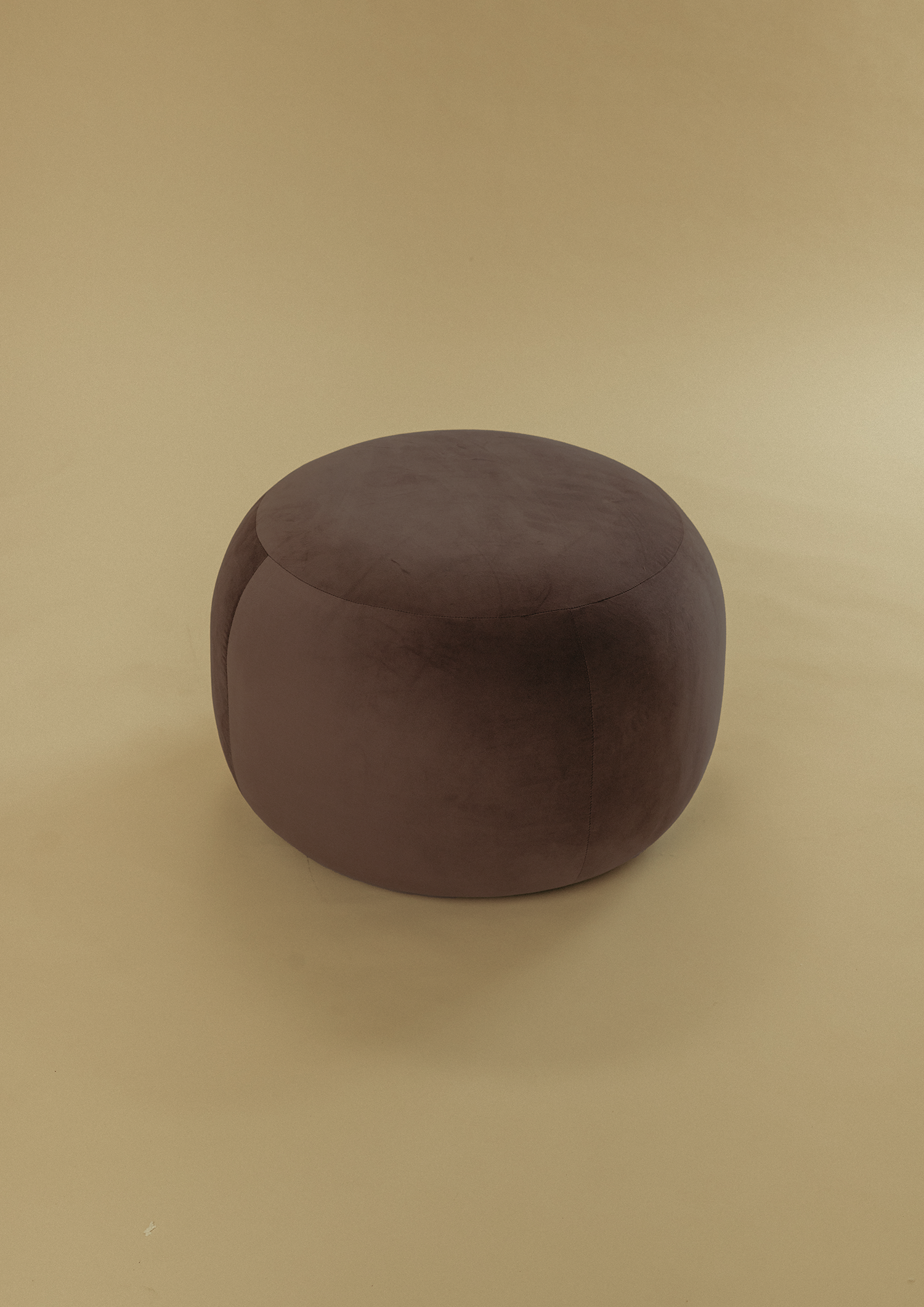 Small Pebble Ottoman in dark brown upholstery with a soft rounded form, photographed against a neutral backdrop.