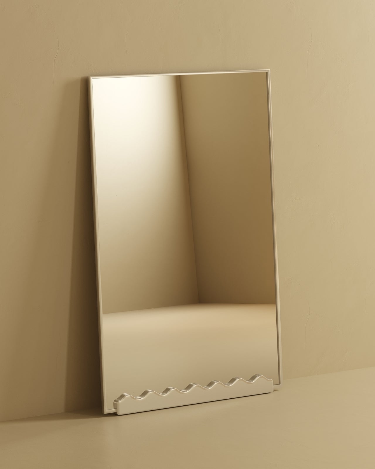 Full-length rectangular mirror with stainless steel frame, leaning against a neutral-toned wall, featuring a sculptural wavy base detail.