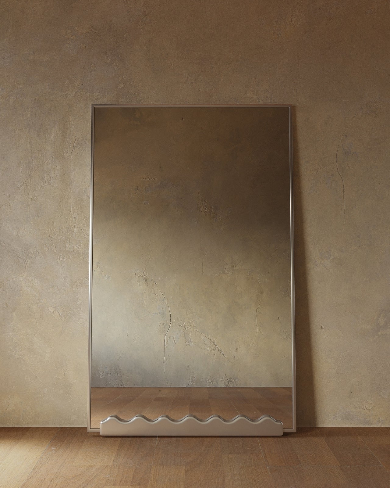 Full-length rectangular mirror with stainless steel frame leaning against a textured wall, featuring a sculptural wavy base detail and reflecting a warm-toned interior.