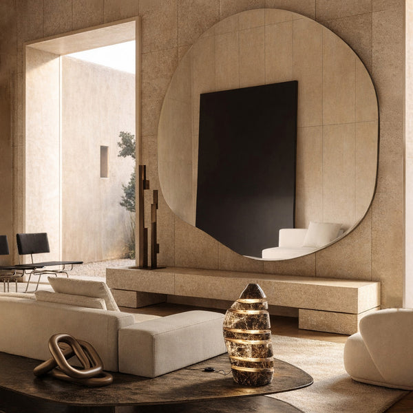 Oversized organic wall mirror above a console in a warm-toned minimalist living room.