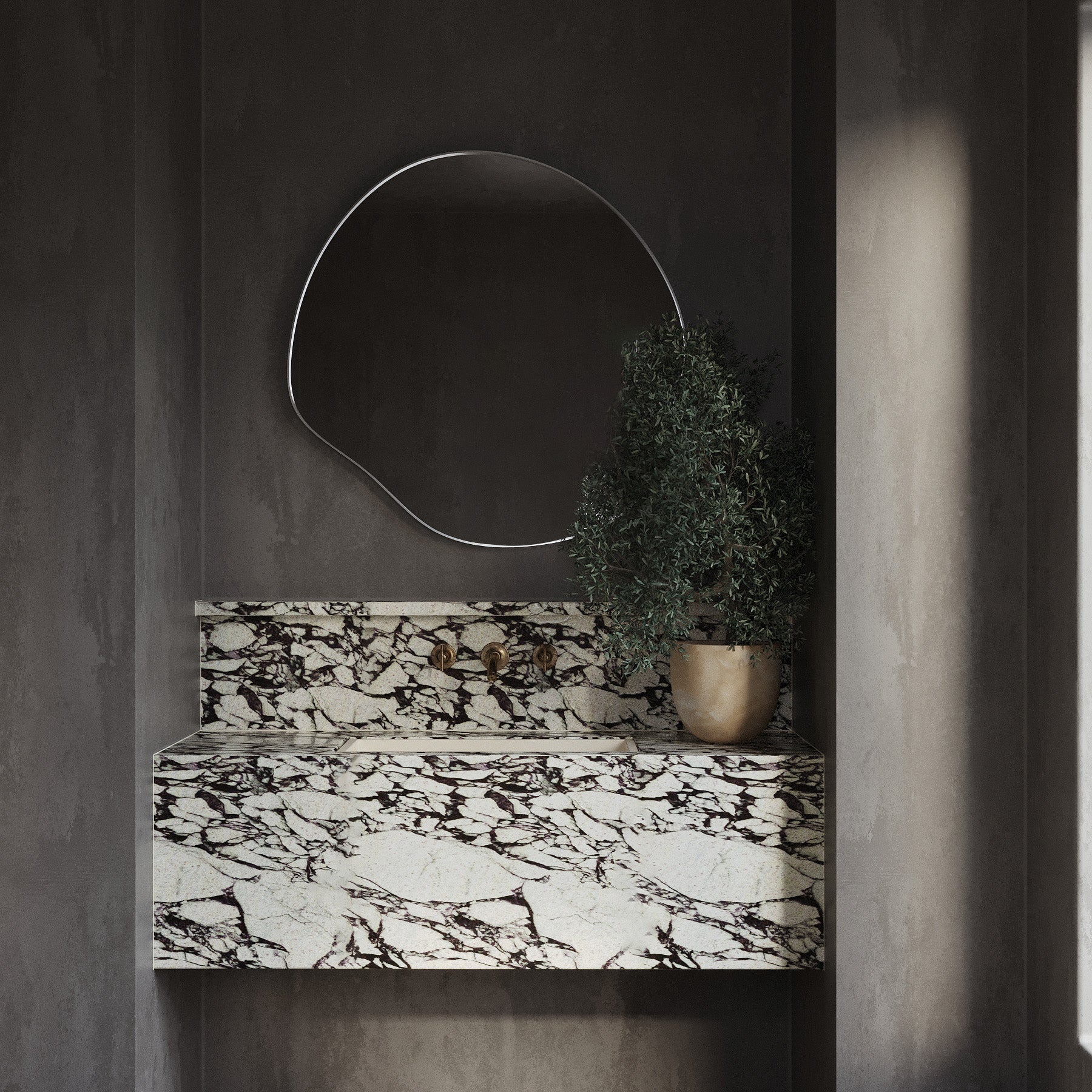 Organic-shaped stainless steel framed wall mirror mounted above a marble vanity in a modern bathroom.