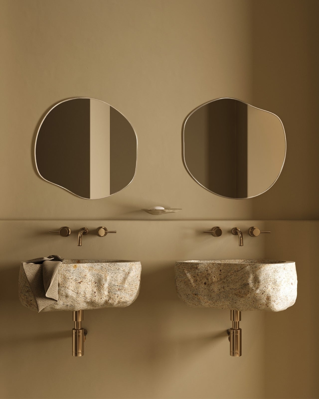 Organic-shaped stainless steel framed wall mirrors mounted above stone wall-mounted sinks in a modern bathroom.
