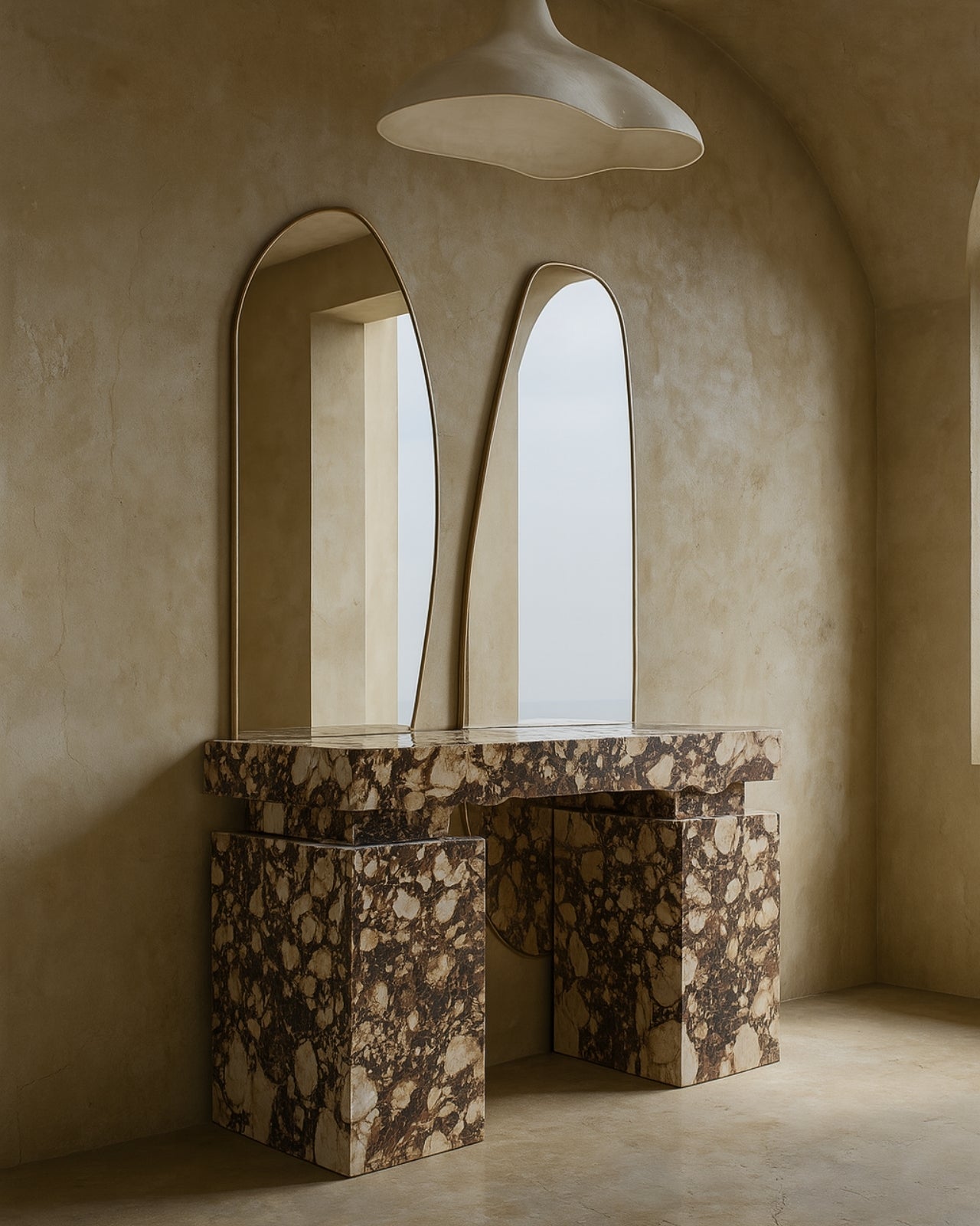 Two asymmetrical brass-framed full length mirrors mounted above a sculptural marble vanity.