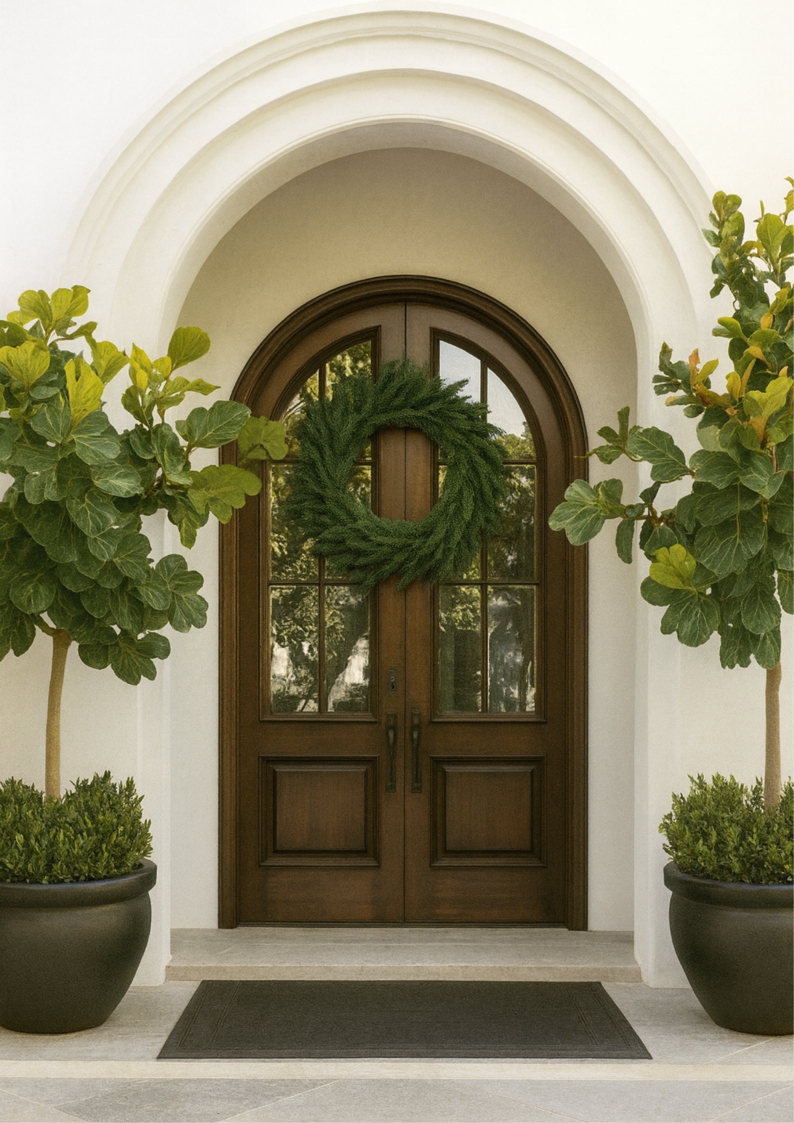 The Self-Manifesting evergreen wreath displayed on a wooden front door, featuring a full green pine design arranged in a circular shape for holiday decor.