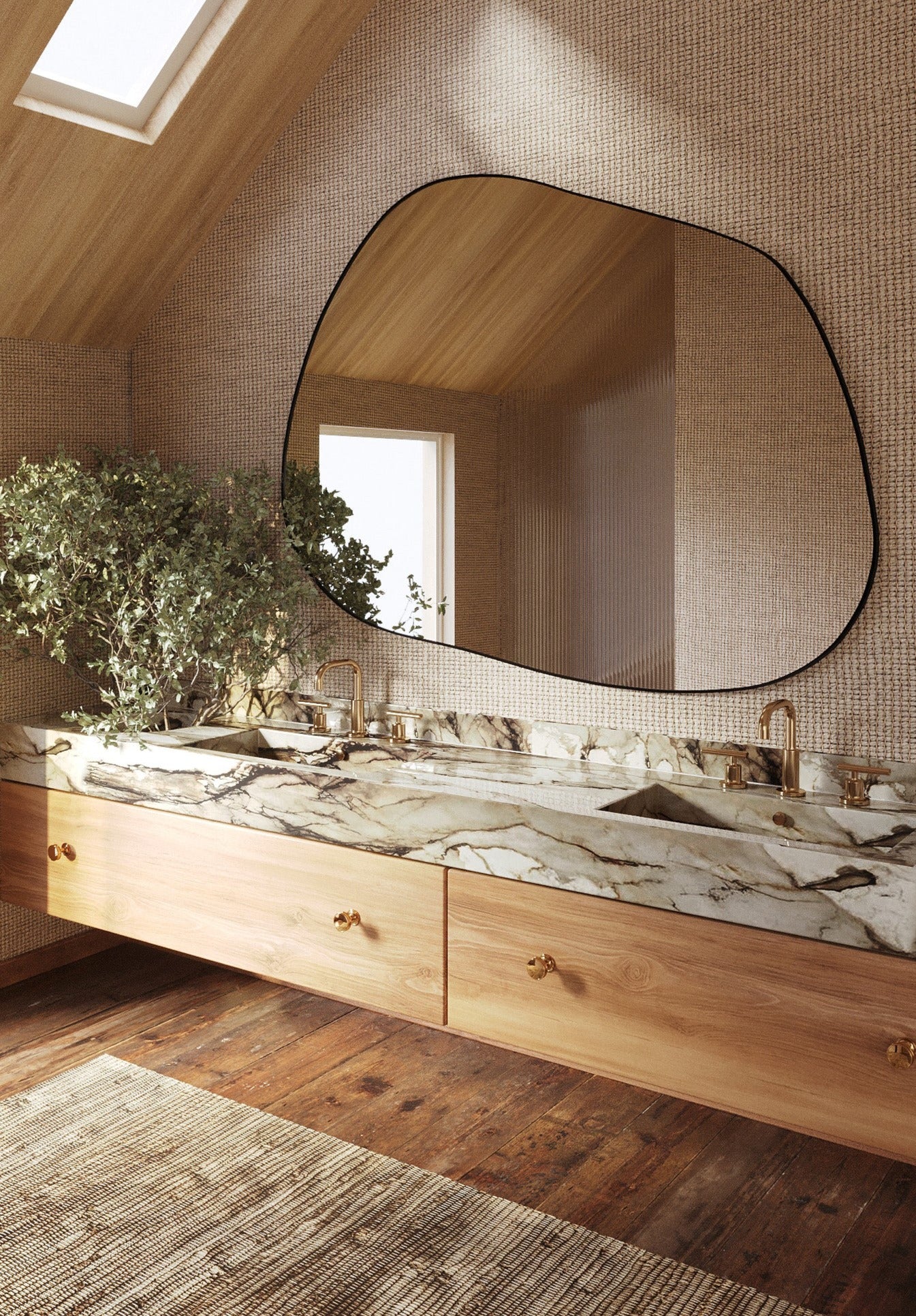 Asymmetrical wall mirror mounted above a double marble bathroom vanity with brass fixtures and wood cabinetry in a warm, naturally lit space.