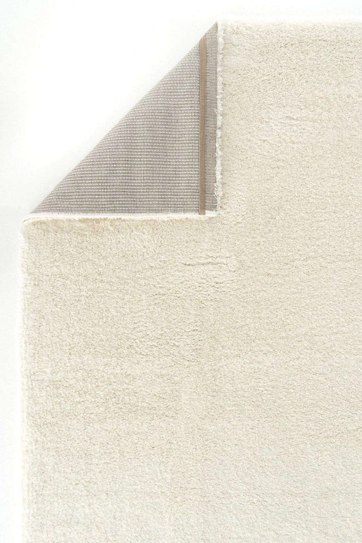 Corner of beige plush rug showing soft pile and backing.