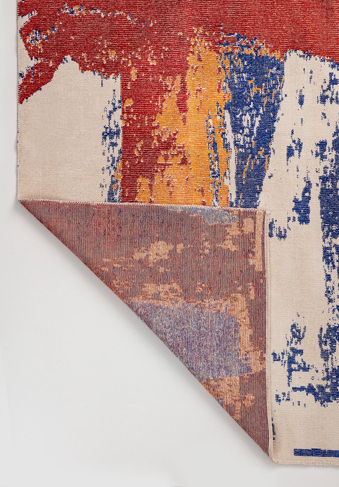 Close-up of abstract multicolor flat-woven rug with folded corner detail.
