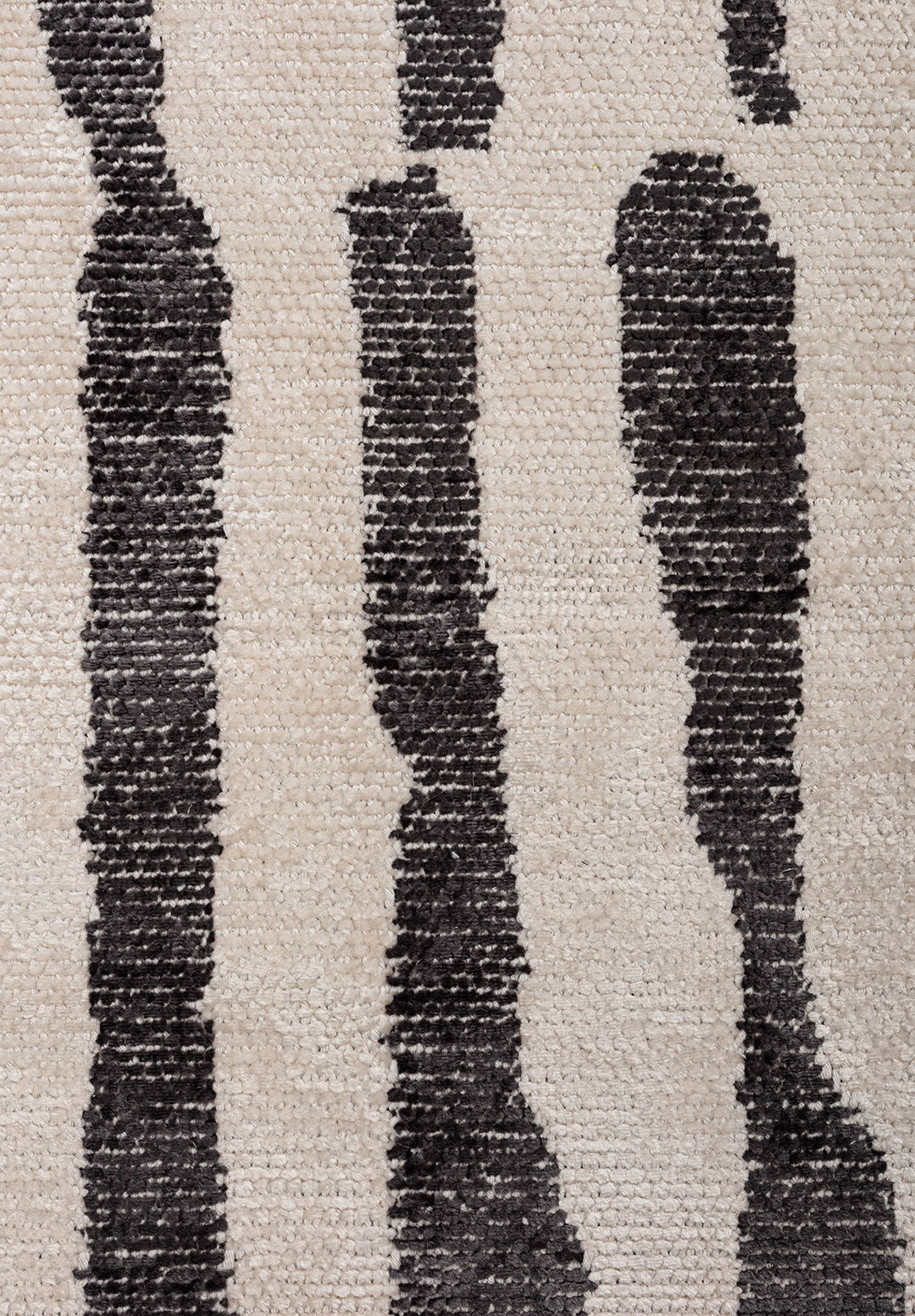 Close-up of a flat-woven rug with irregular black stripes on a light beige background.