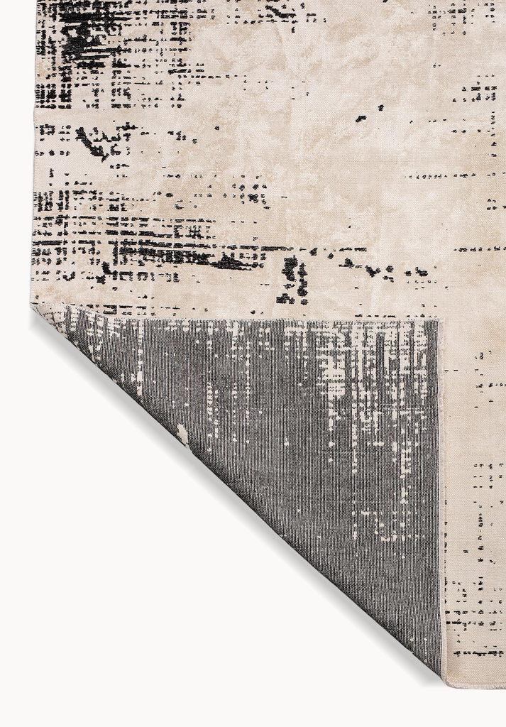 Detail view of a flat-woven rug corner with beige patterned surface and gray backing.