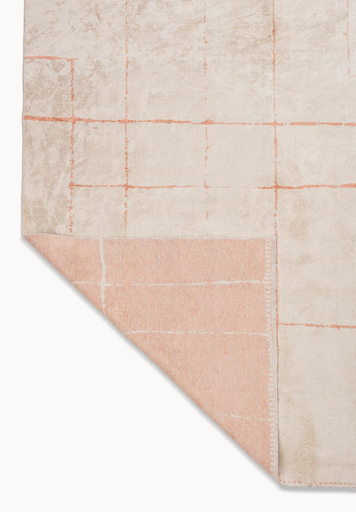 Corner of a beige area rug with subtle blush grid pattern and flat-woven backing.