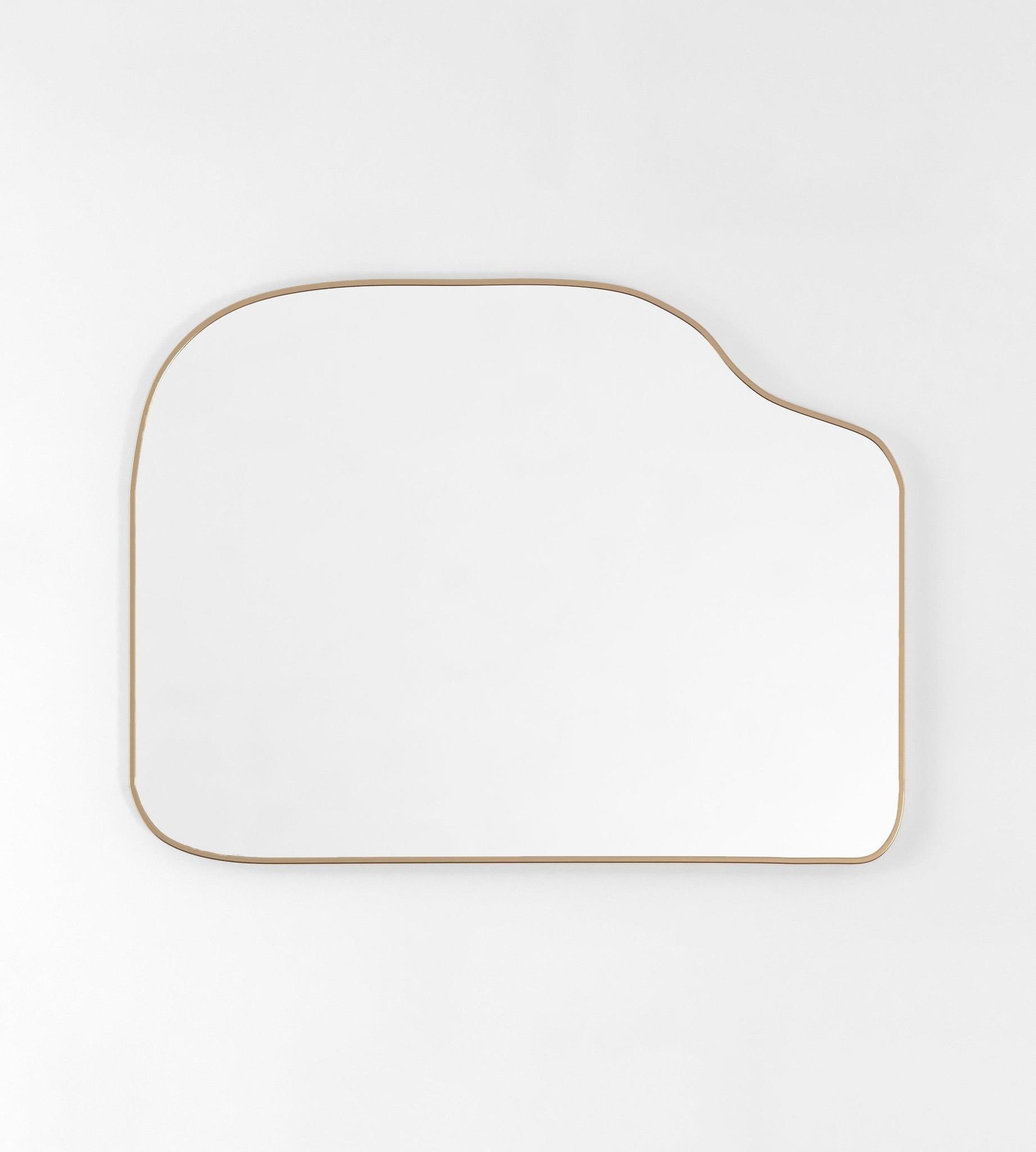 Asymmetrical brass-framed mirror with a horizontal orientation against a white background.