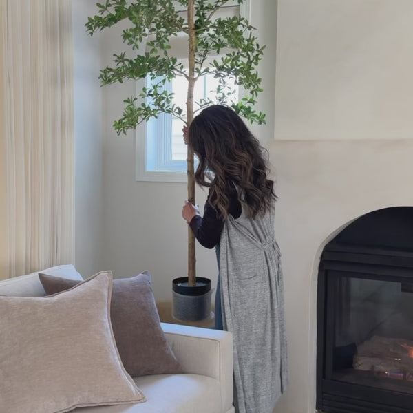 A woman decorates a full-length mirror in her living room as natural daylight fills the space and reflects across the room.